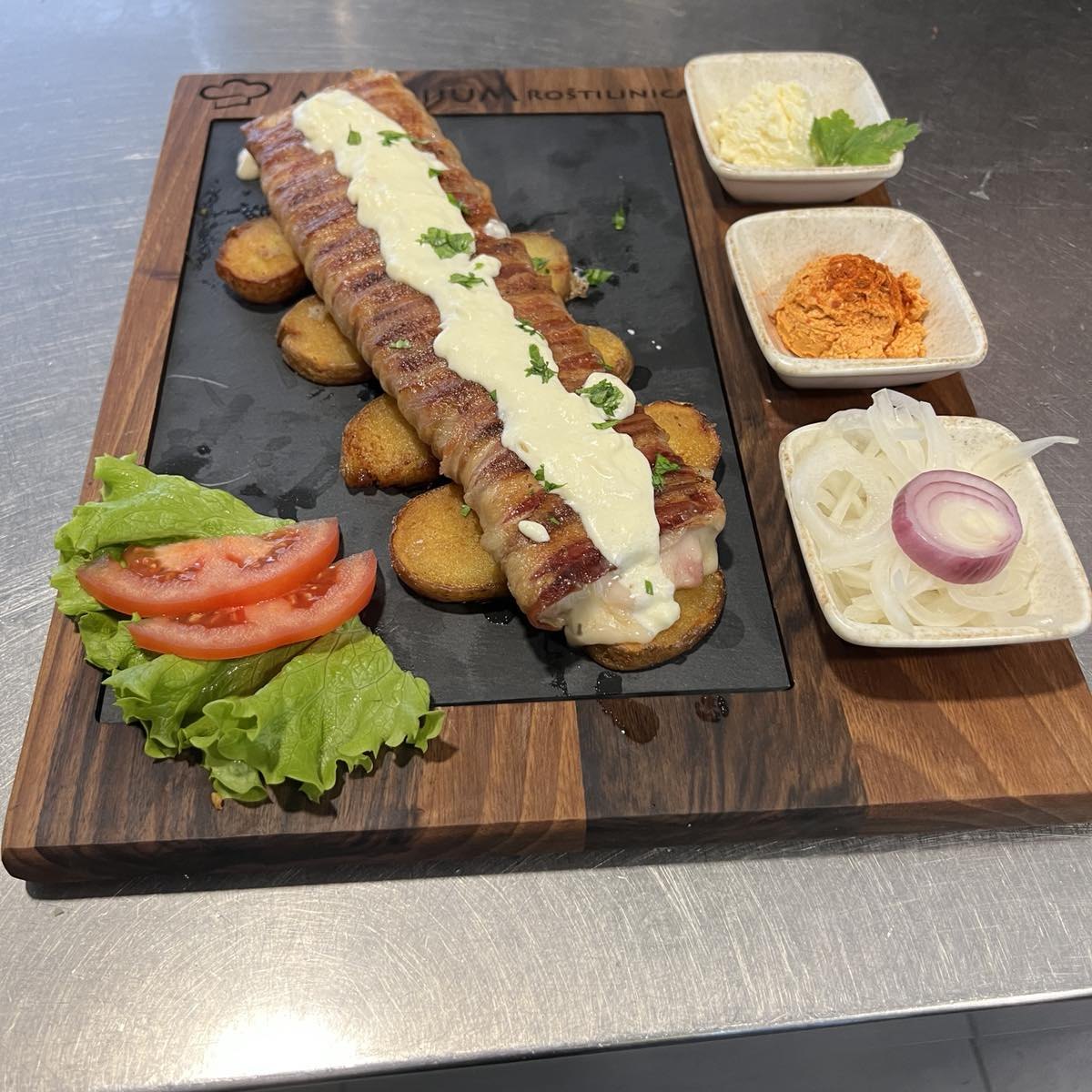 Jelo sa roštilja na brendiranoj dasci restorana, uz tri priloga u zdjelicama